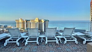 A rooftop terrace with white lounge chairs and a view of the ocean.