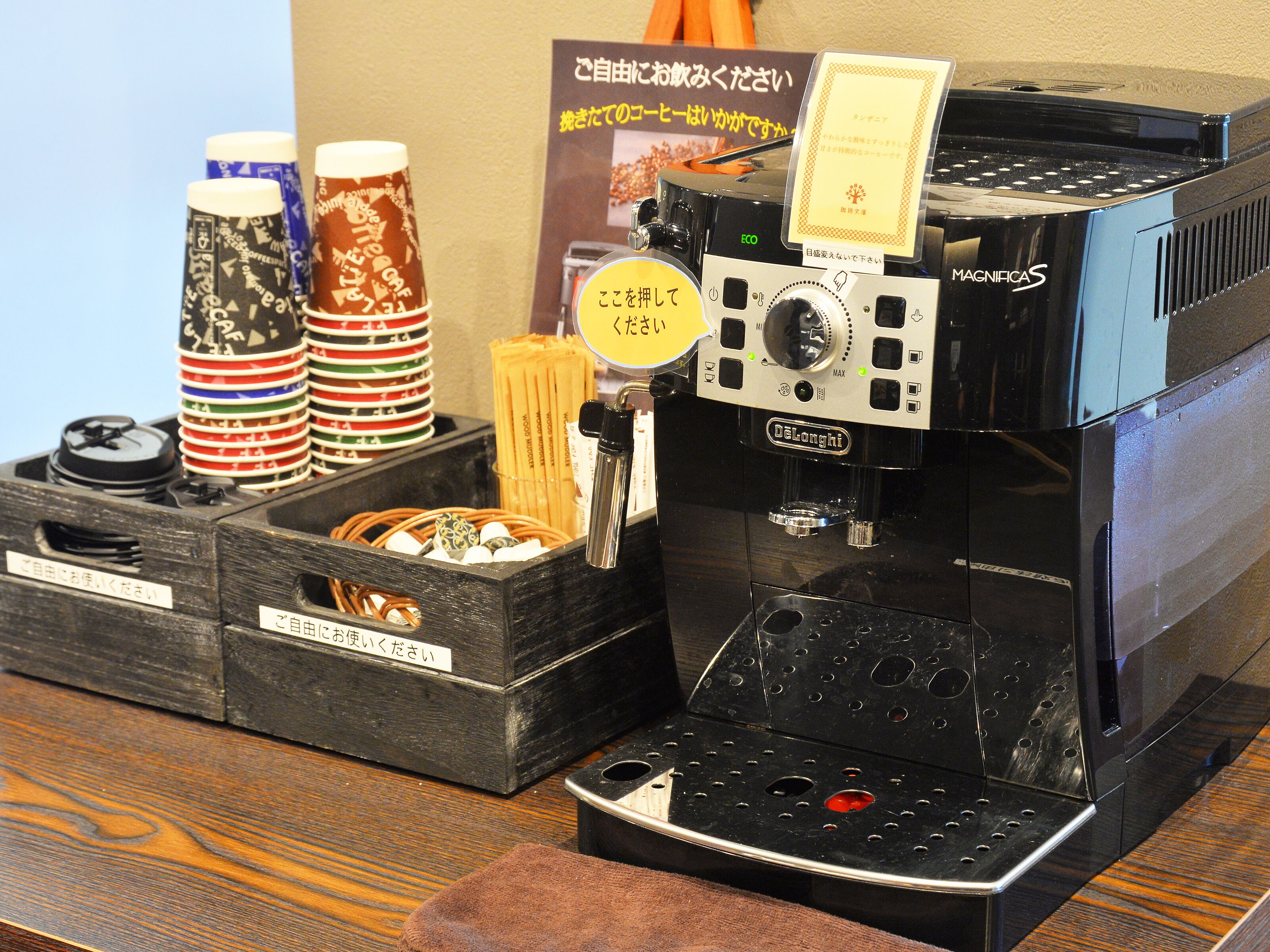 Una máquina de café con un panel de control, un portavasos para tazas de café y un letrero con texto en japonés.