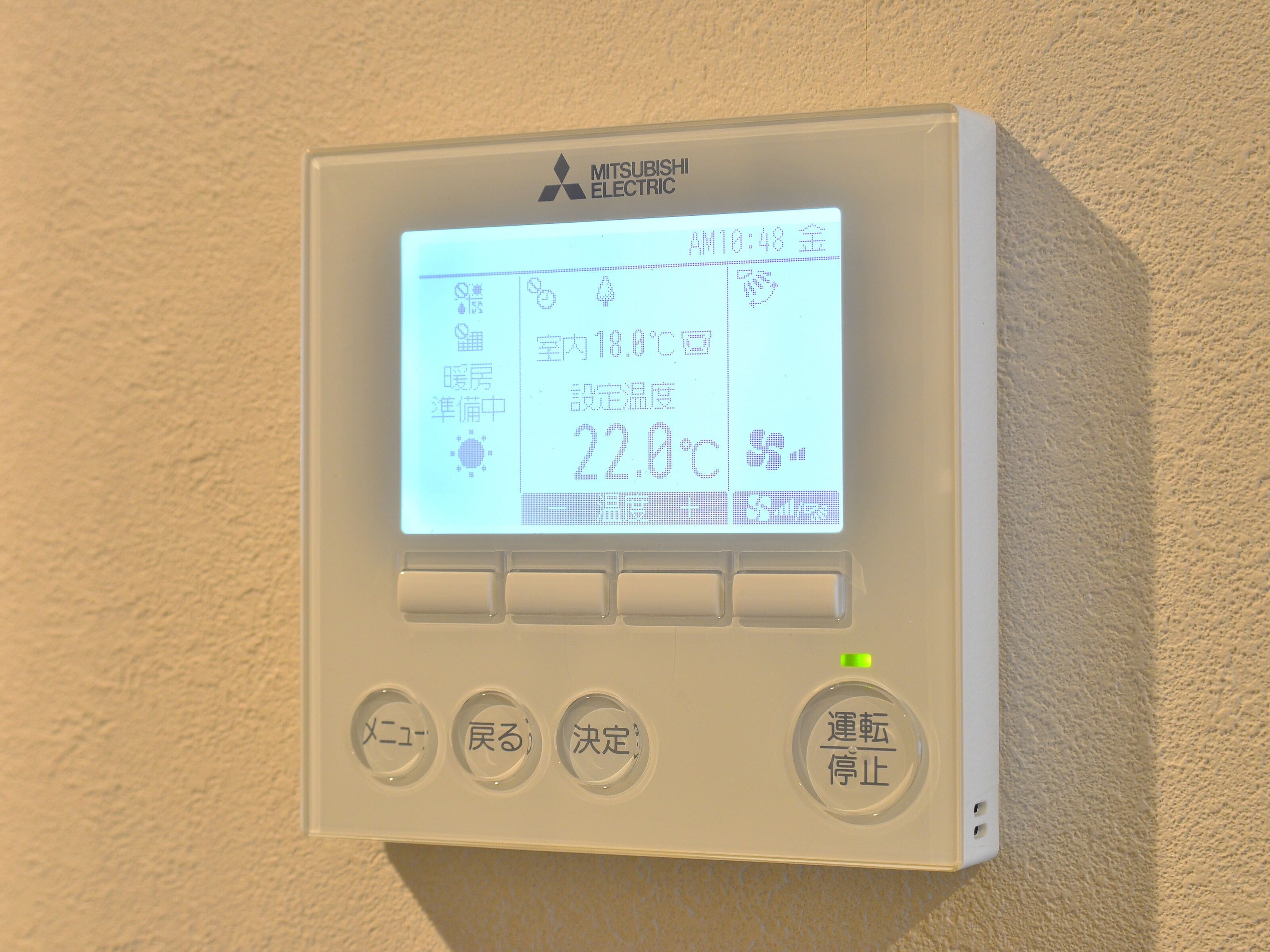 A Mitsubishi Electric thermostat displaying room temperature and time.