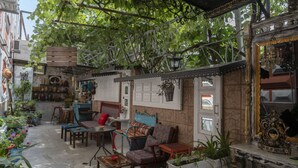 A cozy outdoor seating area with rustic furniture, potted plants, and a decorative mirror. - Elia Boutique Hostel & Apart-Hotel (Tbilisi)