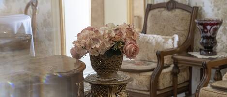 Een kamer met een tafel, een stoel en een decoratieve vaas met bloemen.