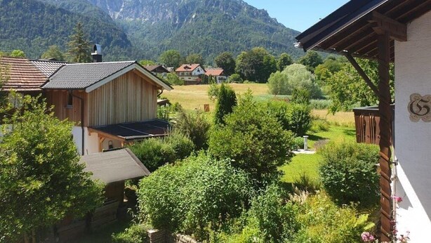Ein Wohngebiet mit Häusern, einem Garten und Bergen im Hintergrund.