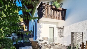 Eine Terrasse mit Tisch und Stühlen, einem Holzzaun und Kübelpflanzen.