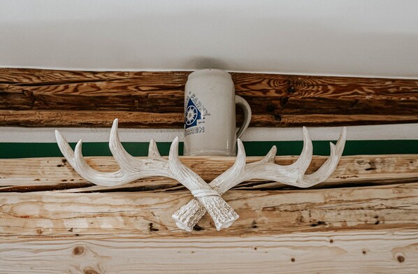 A mug with a logo and antlers on a wooden surface. - Gasthaus Hirsch (Wangen im Allgäu)