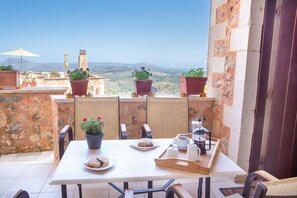 A terrace with a table set for breakfast, potted plants, and a view of the countryside. - 90m Double Room Maisonette With Valley, Mountain and sea View (Apokoronas)