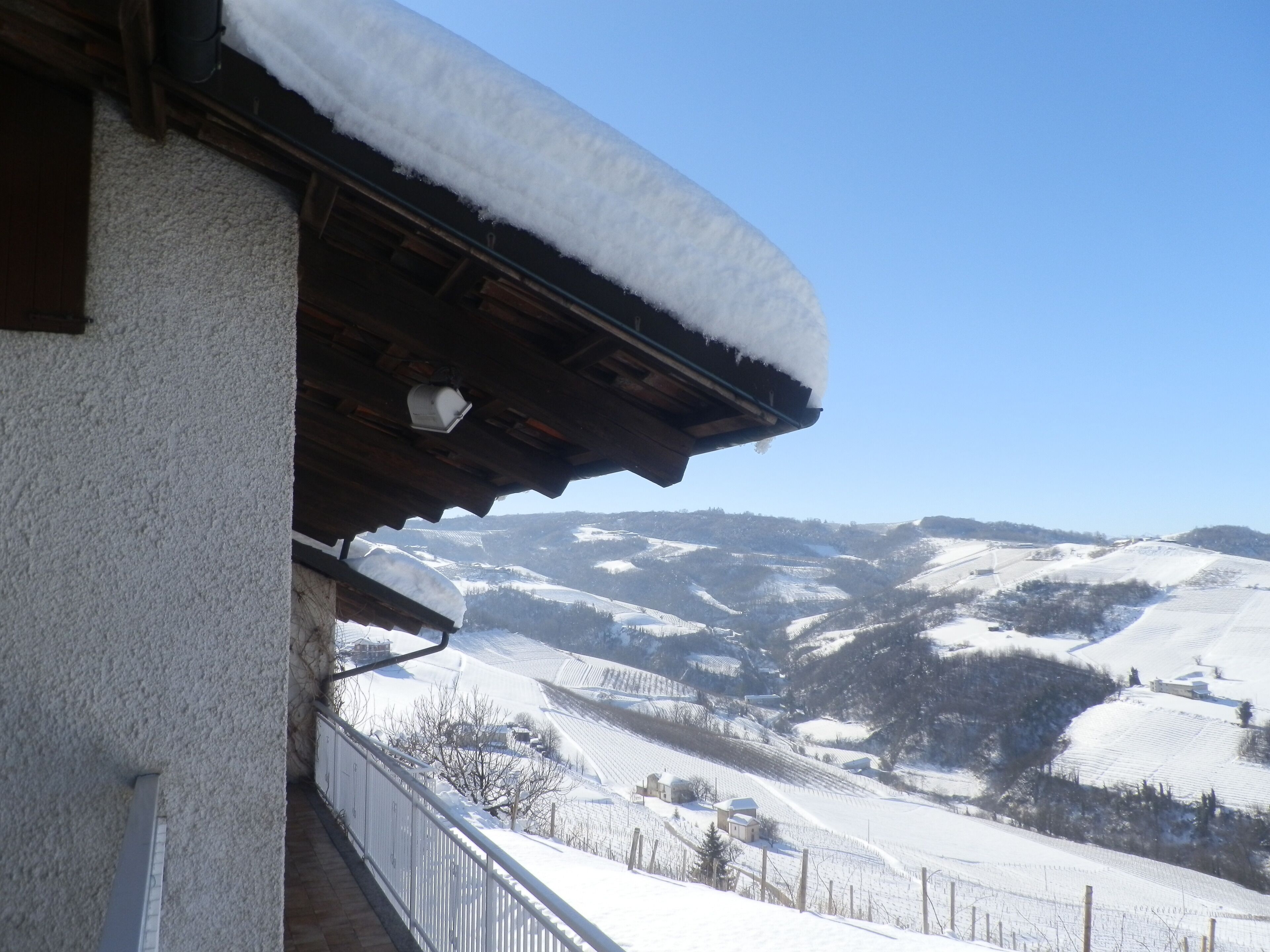 A snow-covered balcony with a view of a mountainous landscape.