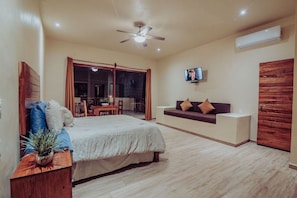 Un dormitorio con cama, sofá, televisión y ventilador de techo.