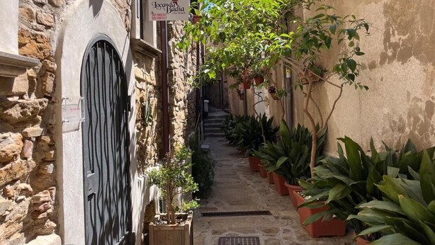 A narrow stone alley with a sign for 'Jocundia Badiya' and potted plants lining the path. - Locanda Badia Residenze Iride e Celeste (Castellabate)