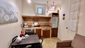 A compact kitchen with a dining table, chairs, a refrigerator, and a window. - Locanda Badia Residenze Iride e Celeste (Castellabate)