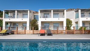 A modern hotel with a pool area, featuring two-story buildings, a wooden deck, and lounge chairs. - RESIDENCE U MANELLU (Santa-Reparata-di-Balagna)