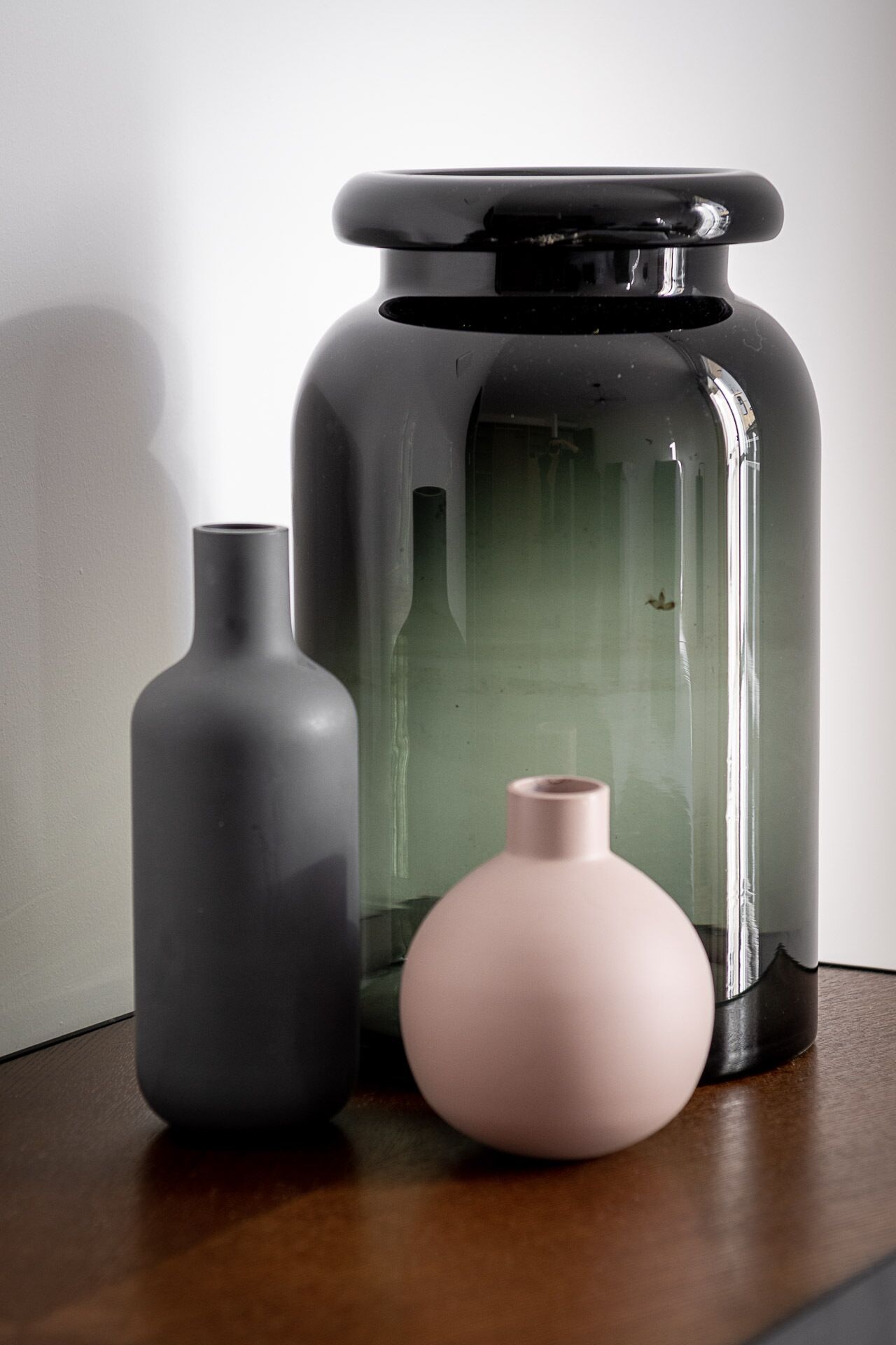 Three ceramic vases of varying sizes and shapes on a wooden surface.