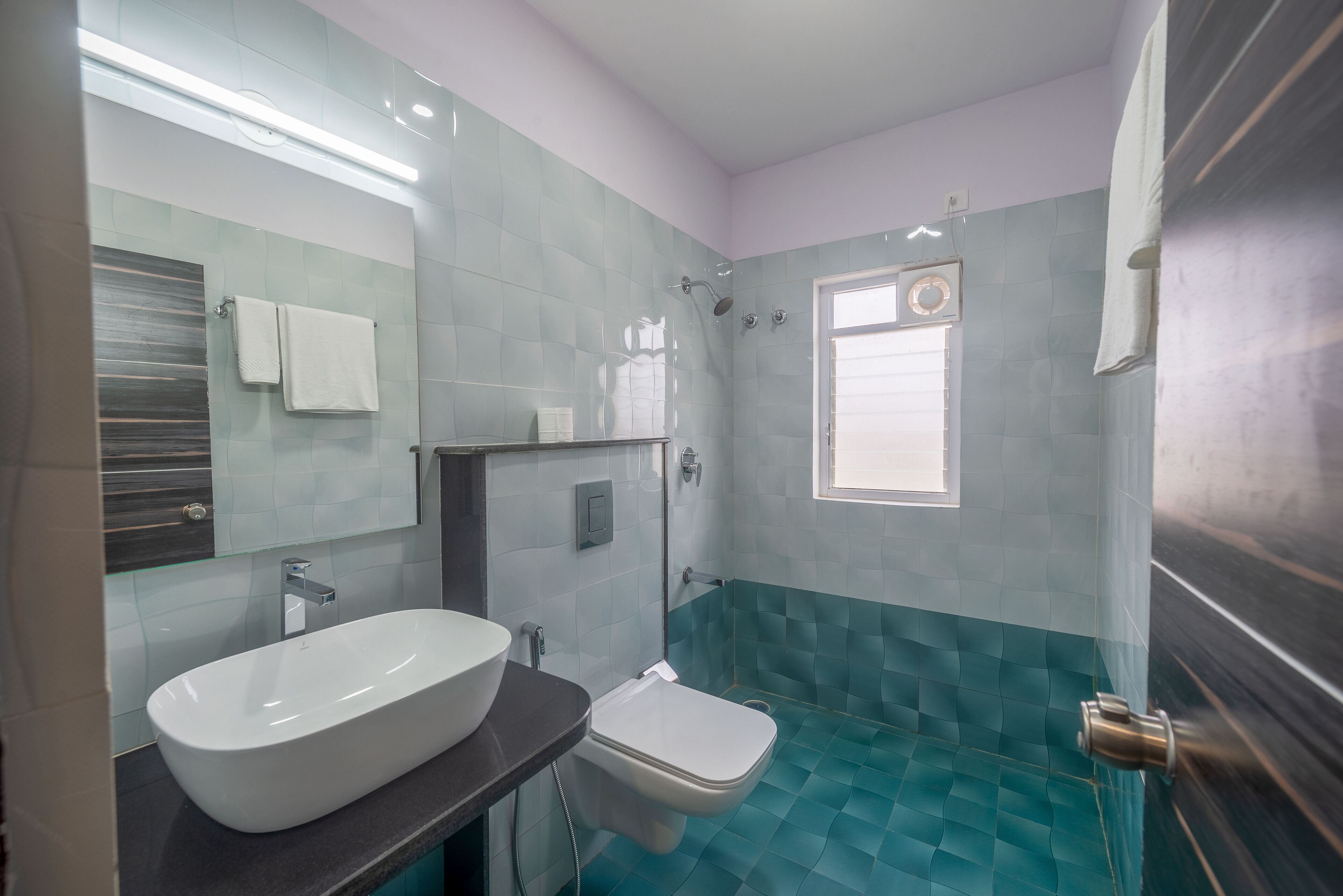 Une salle de bain avec un grand lavabo blanc, des toilettes et un espace douche.