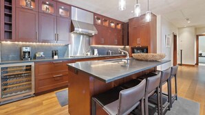 Een moderne keuken met houten kastjes, roestvrijstalen apparatuur en een centraal eiland met barkrukken.