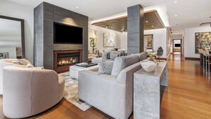 A modern living room with a fireplace, a large flat-screen TV, and contemporary furniture.