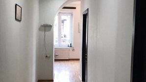 A hallway with wooden flooring, white walls, and a door on the right. - green classic (Tbilisi)