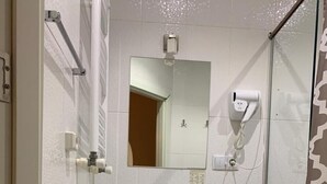 A modern bathroom with a white sink, a mirror, a hairdryer, and a towel rack. - green classic (Tbilisi)