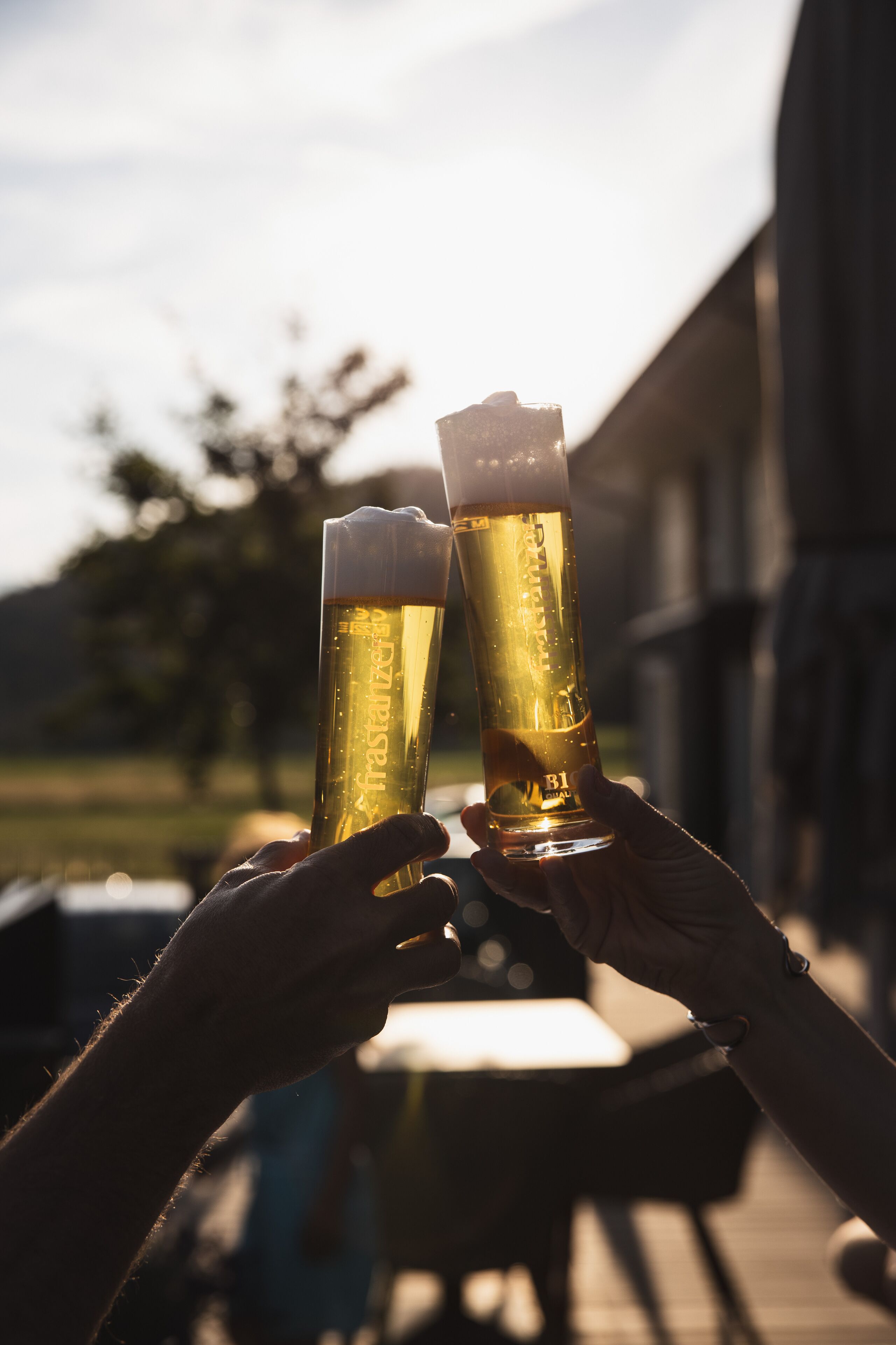 Zwei Personen erheben Biergläser, vermutlich zum Anstoßen.