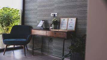 A reception desk with a modern design, a chair, and framed welcome and check-in cards.