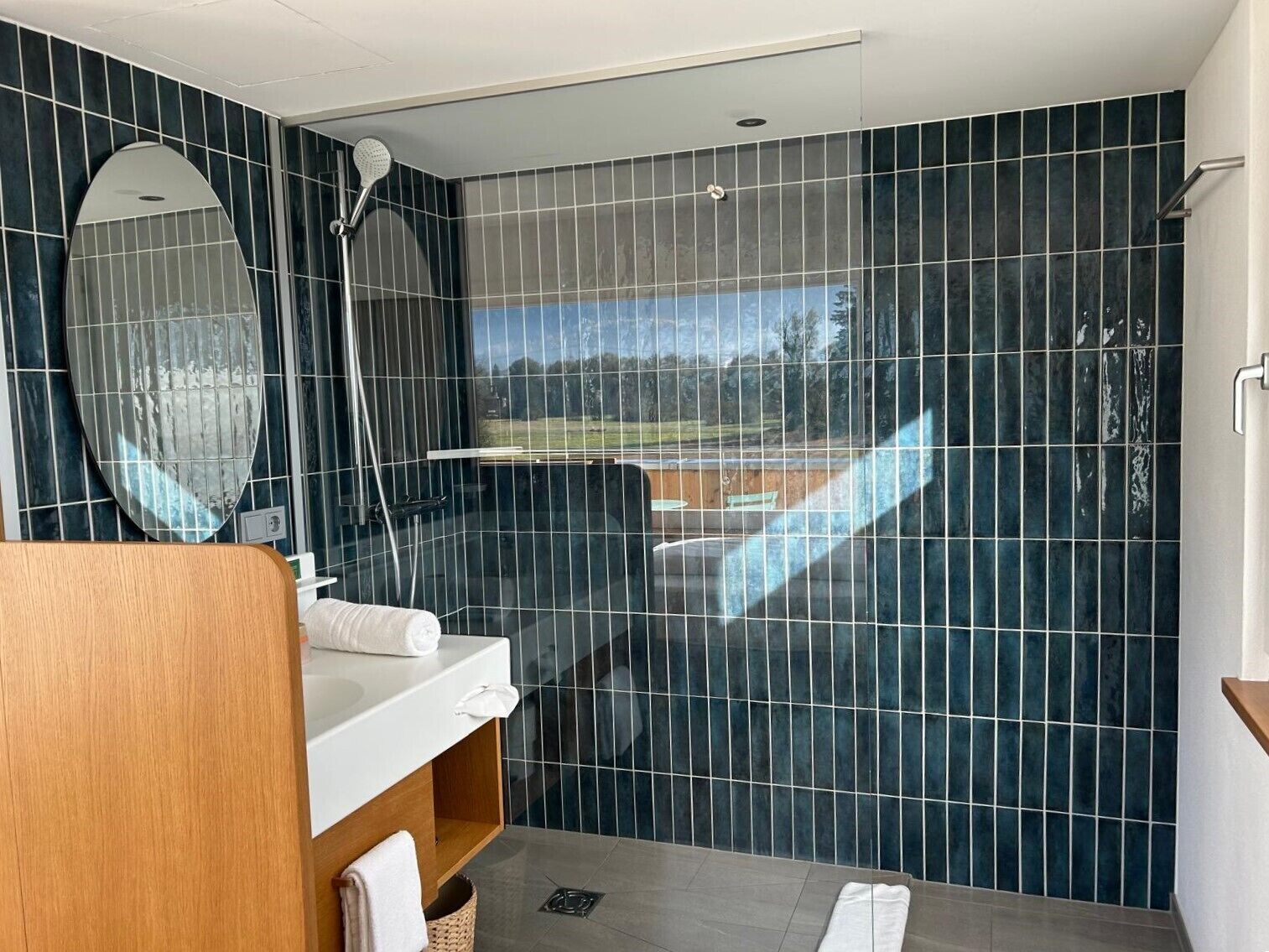 Ein modernes Badezimmer mit Dusche, einem großen Spiegel und Blick ins Freie.