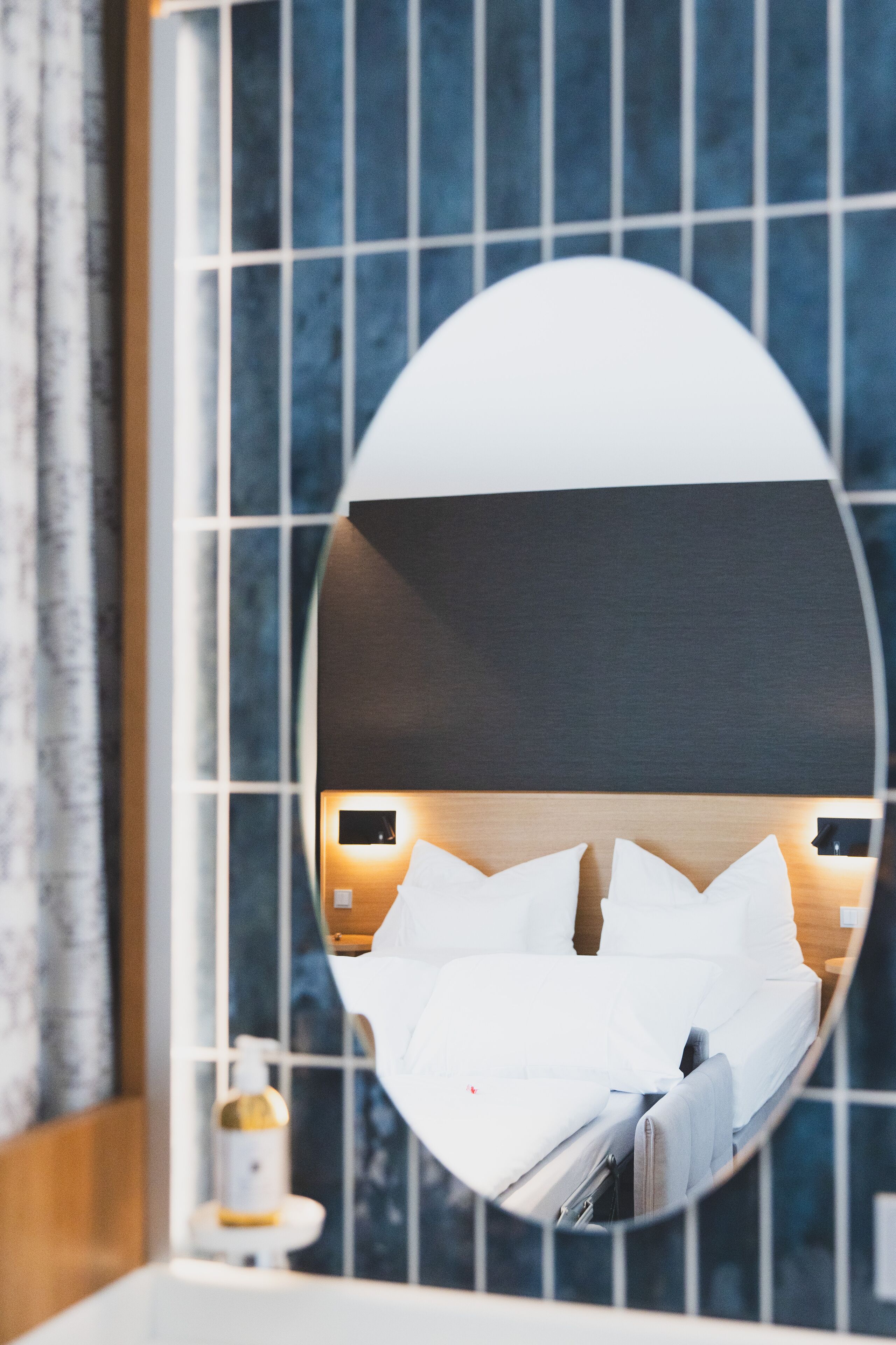 A bathroom with a large mirror, a wooden headboard, and a bottle of lotion on the counter.