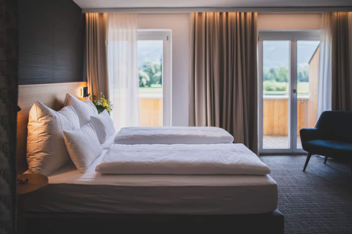 Habitación de hotel con una cama grande, una silla y vistas al exterior a través de una puerta corrediza.