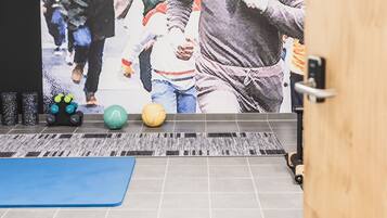 Ein Fitnessstudio mit einer großen Wandmalerei von Läufern, Übungsbällen und einer blauen Matte auf dem Boden.