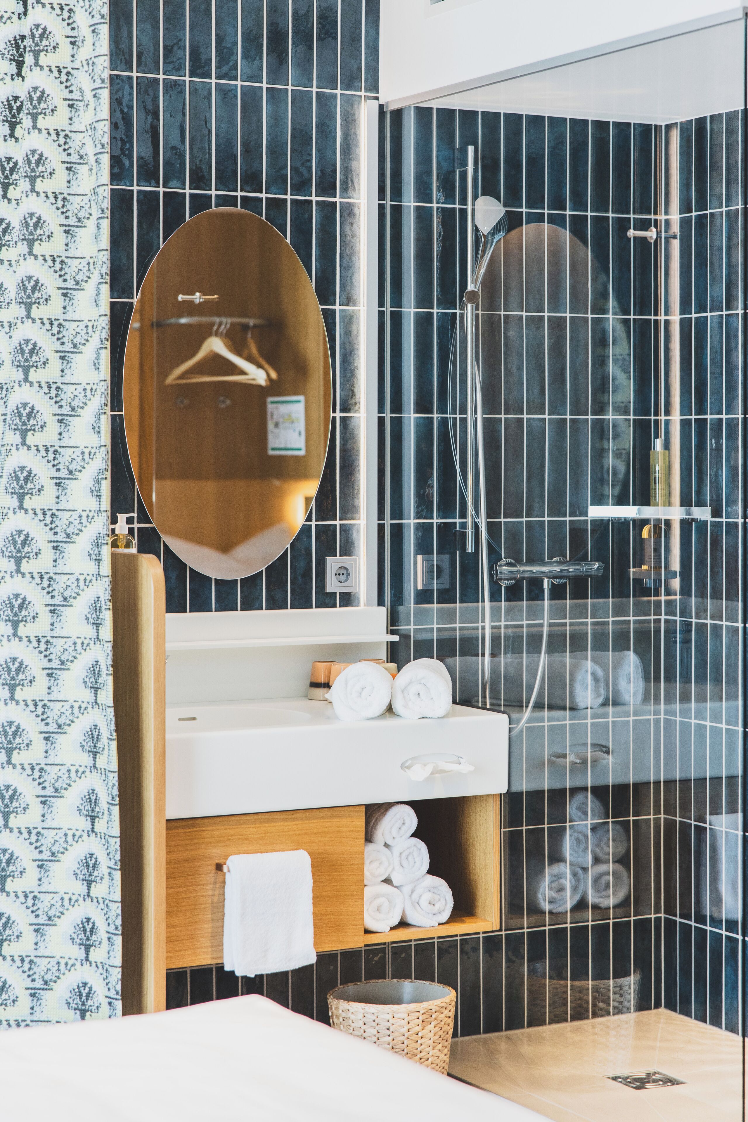 Un baño moderno con tocador de madera, un espejo grande y ducha con mampara de vidrio.