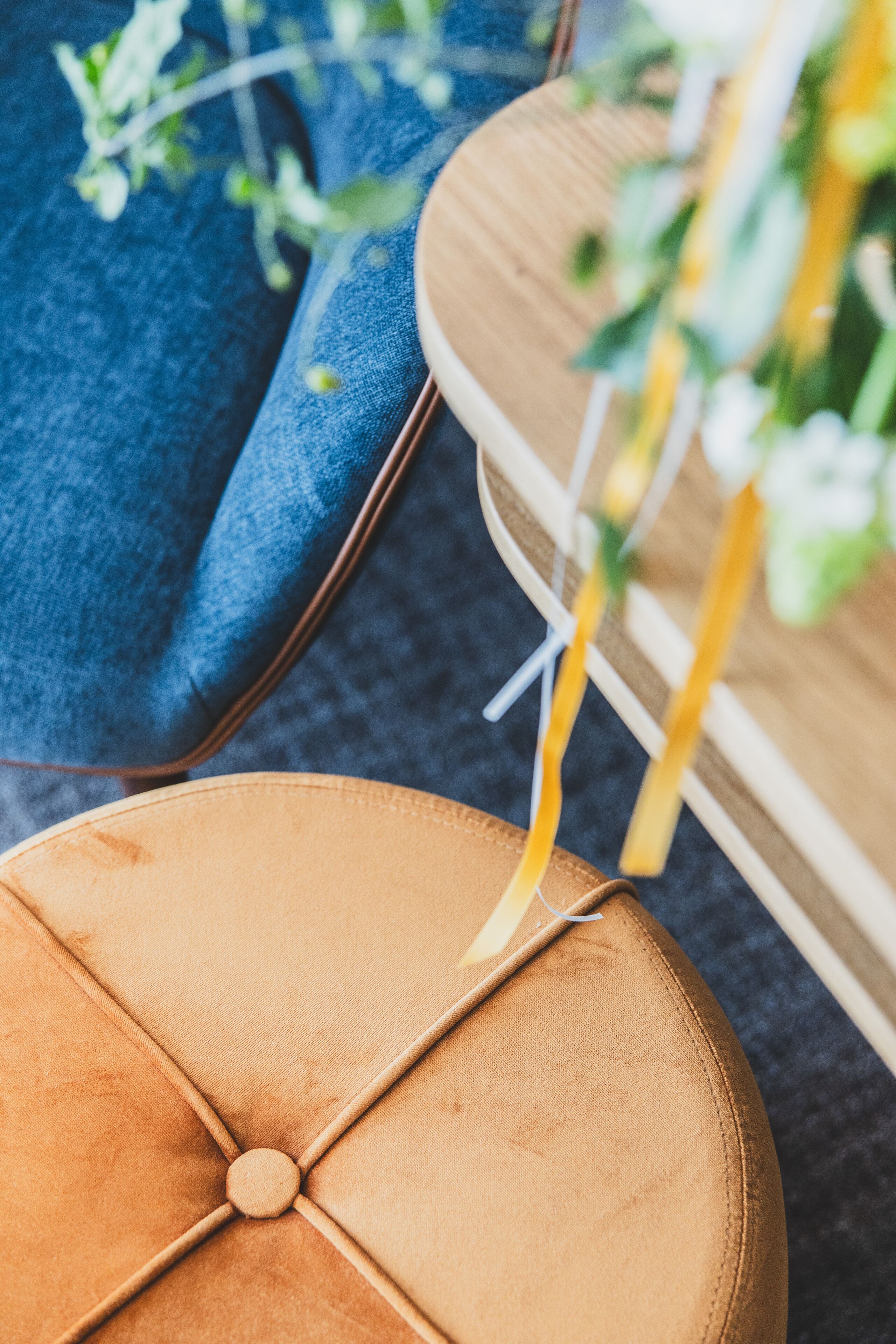 A close-up of a round, cushioned ottoman with a button in the center, placed on a blue fabric surface.