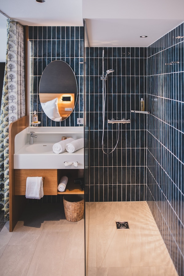 Un baño moderno con lavamanos, espejo y ducha.