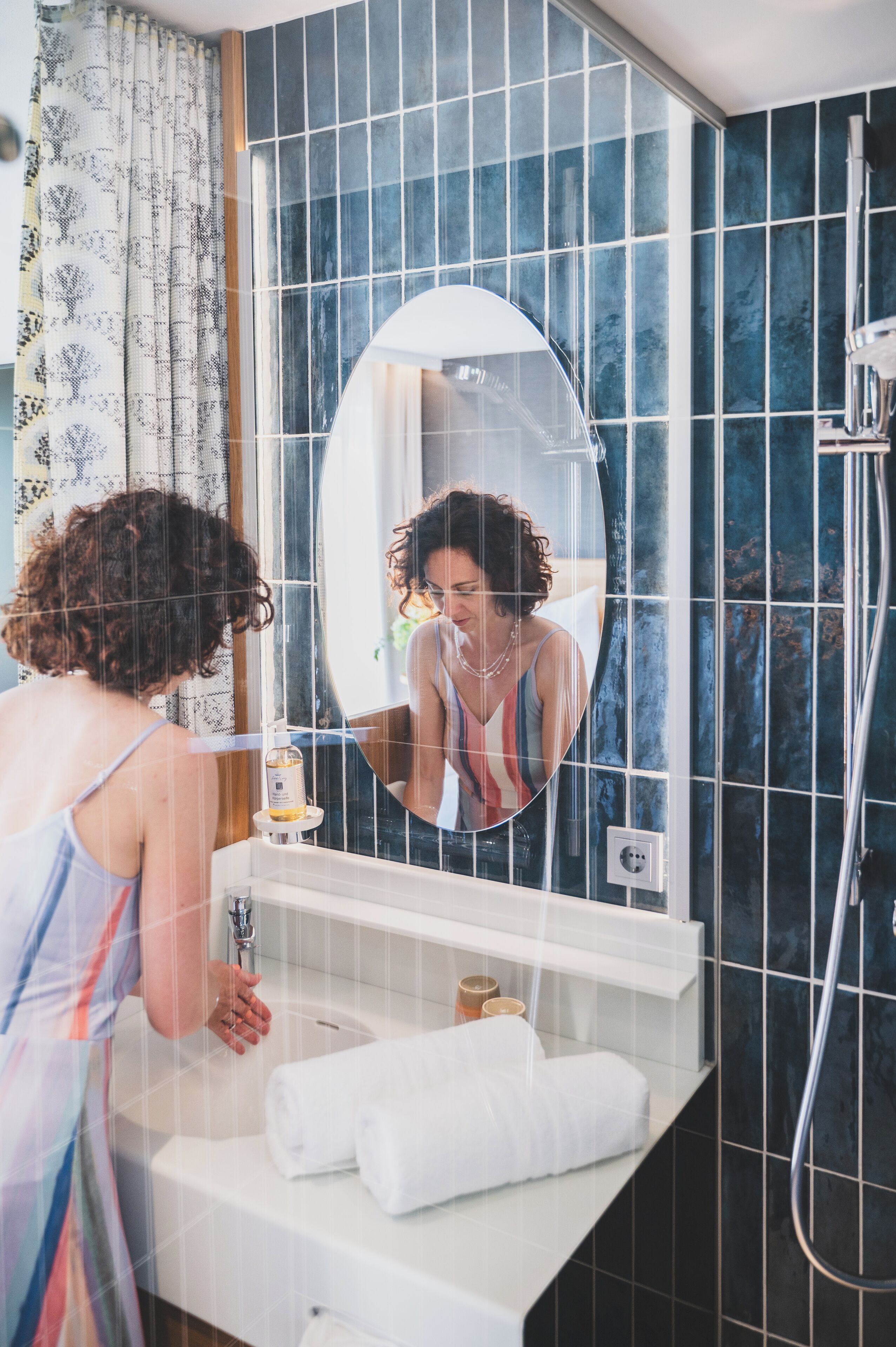 A bathroom with a large mirror, a sink, and a shower.