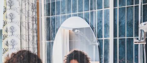 A bathroom with a large mirror, a sink, and a shower.