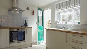 Una cocina moderna con armarios blancos, horno integrado y ventana con vistas al exterior.