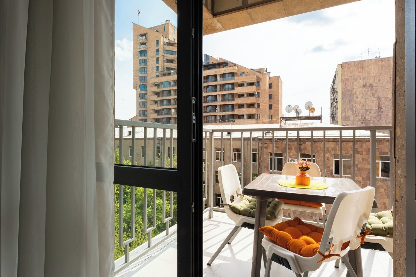 Un balcone con tavolo, sedie e vista sugli edifici circostanti.