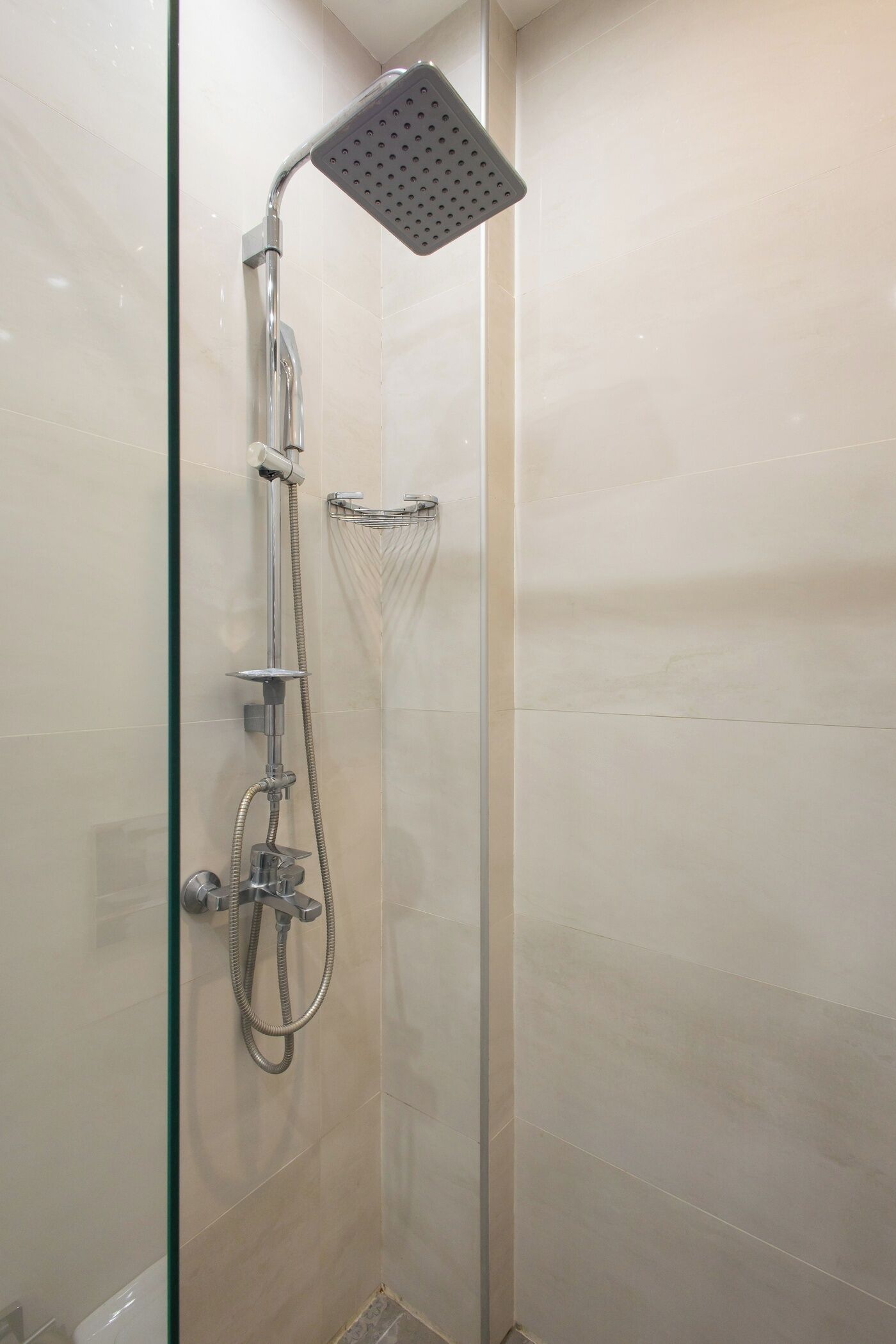 Ducha envuelta en vidrio, con un cabezal de ducha manual y otro fijo.