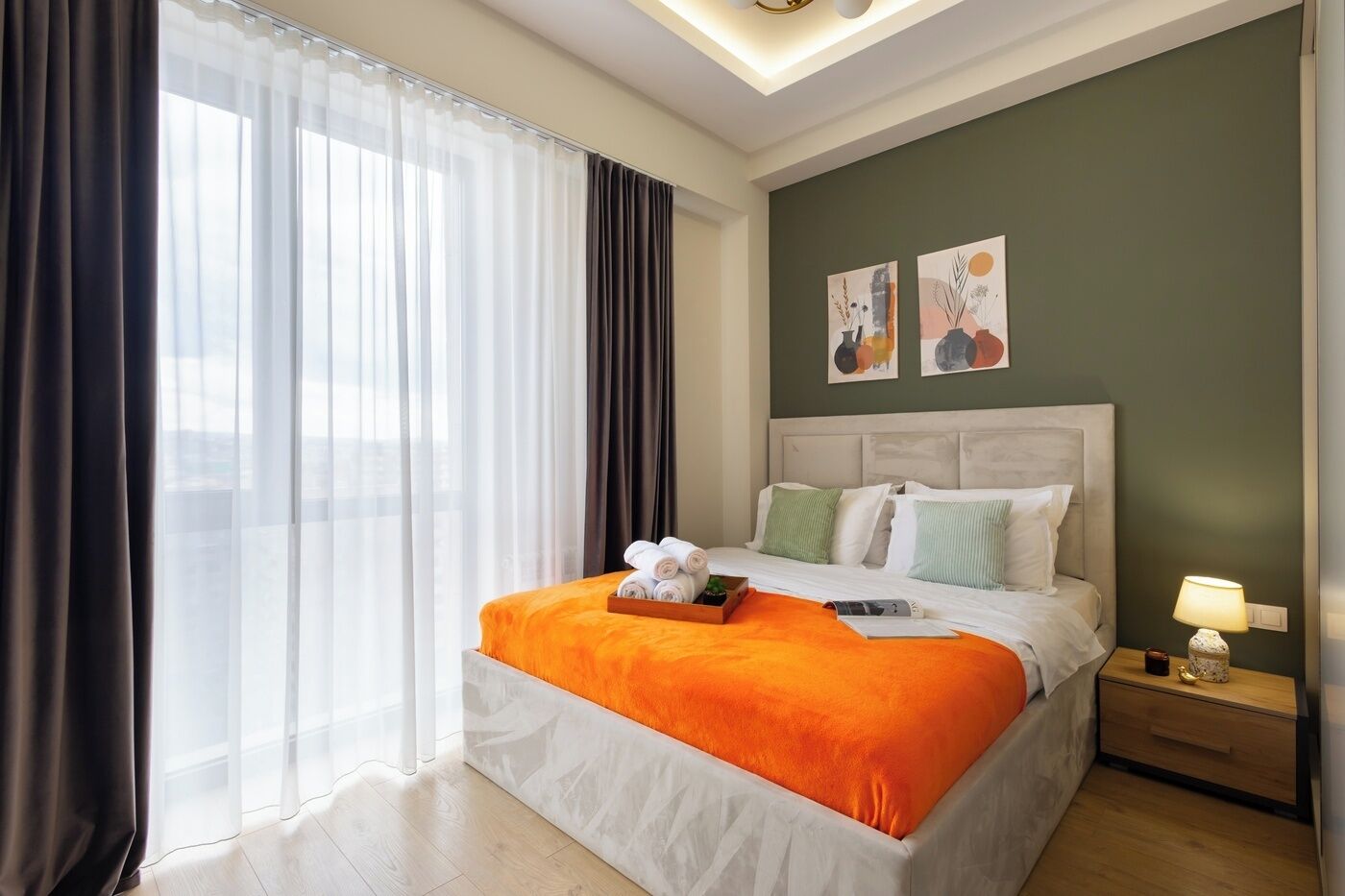 A hotel room with a bed, a nightstand, a lamp, and artwork on the wall.
