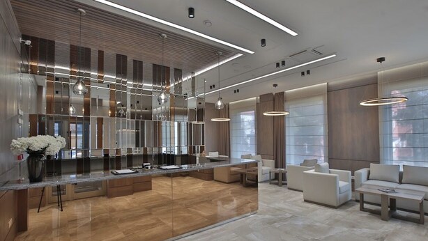 A modern hotel lobby with a central island, seating area, and large windows. - Central Park Resident (Bishkek)