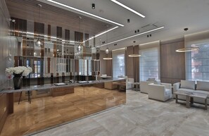 A modern hotel lobby with a central island, seating area, and large windows. - Central Park Resident (Bishkek)