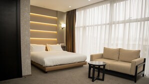 A hotel room with a bed, a sofa, and a small table. - Central Park Resident (Bishkek)