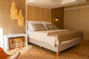 A modern bedroom with a large bed, a bedside table, a wall-mounted lamp, and a woven basket. - Deluxe Double Room with Balcony (Veiros)