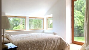 A bedroom with a large window, a bed, and a nightstand. - Architect's house - 10000m2 garden and undergrowth (Bains-sur-Oust)