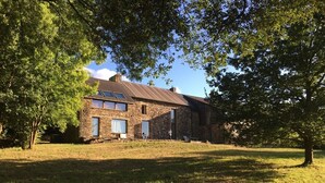 A stone house with a sloped roof, large windows, and a grassy yard. - Architect's house - 10000m2 garden and undergrowth (Bains-sur-Oust)