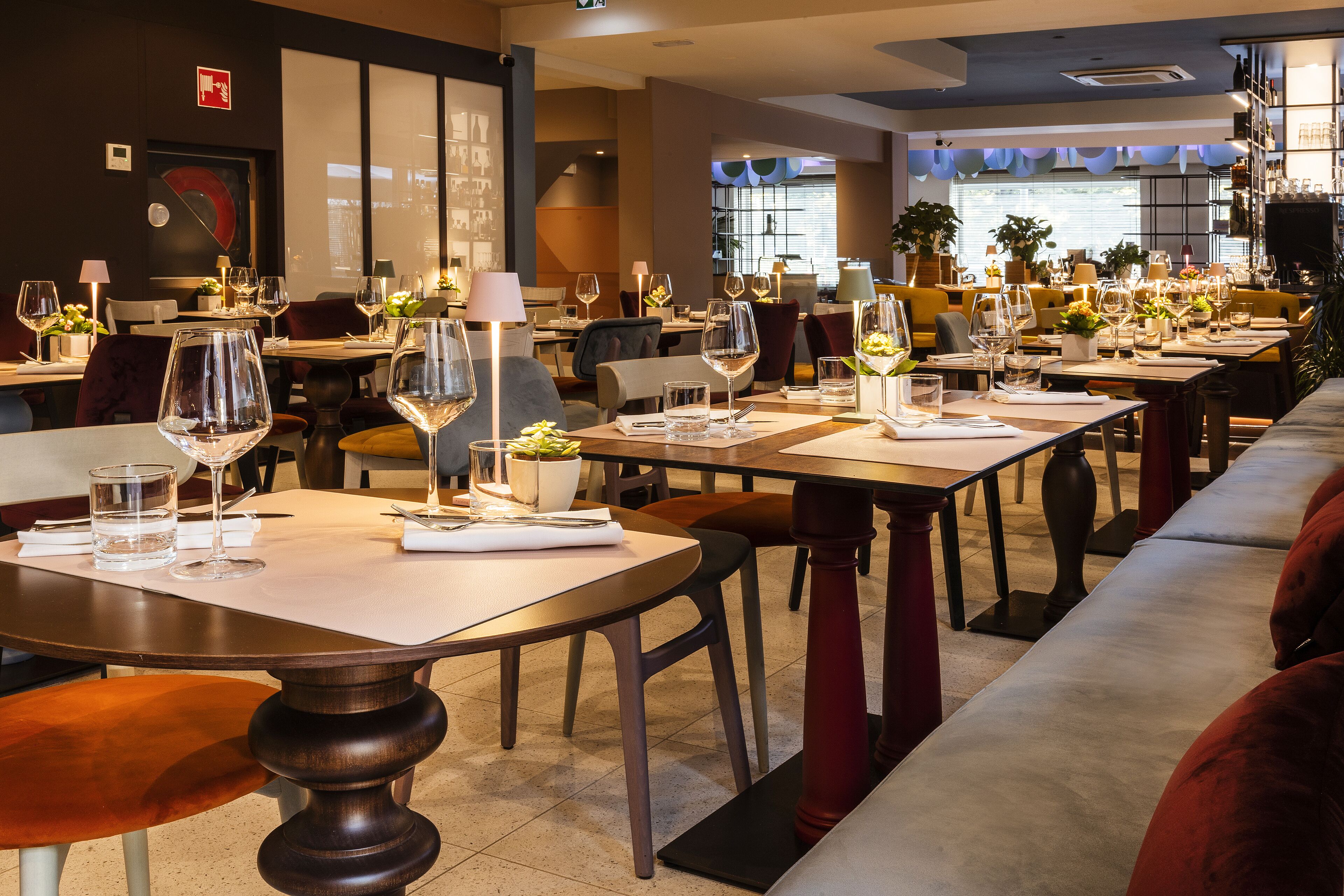Un restaurante con varias mesas dispuestas para comer, con copas de vino y vasos de agua.