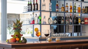 A bar area with shelves of liquor bottles and glasses, a pineapple centerpiece, and a fruit bowl. - Adesso Hotel (Rome)