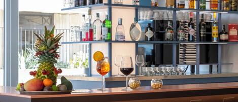 A bar area with shelves of liquor bottles and glasses, a pineapple centerpiece, and a fruit bowl.