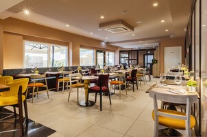 Un ristorante spazioso con diversi tavoli e sedie, ampie finestre e un arredamento moderno.
