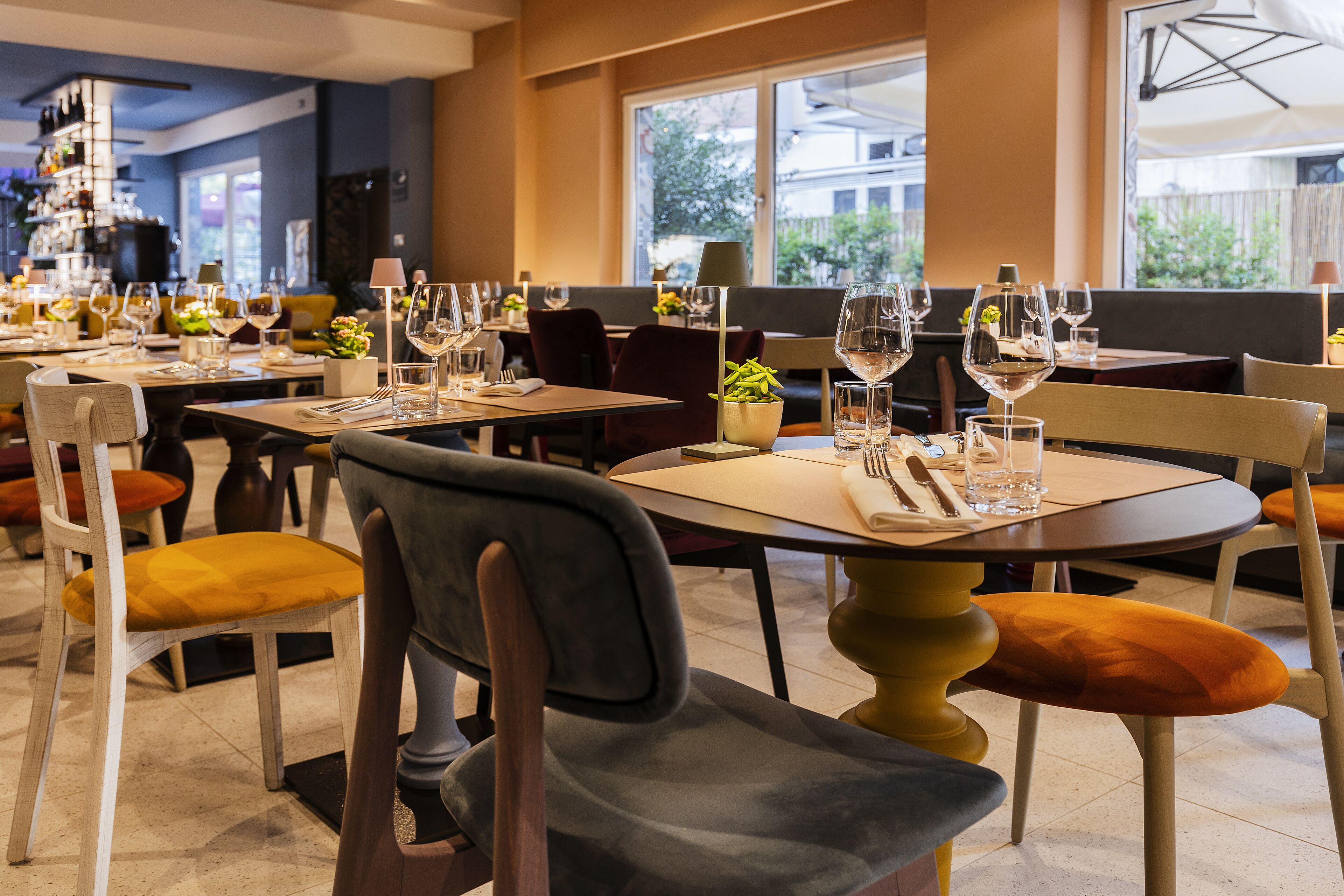 A restaurant with multiple tables set for dining, each with chairs and wine glasses.