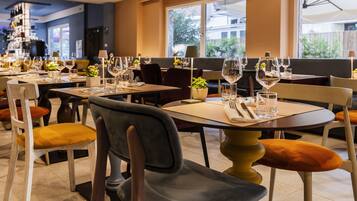 A restaurant with multiple tables set for dining, each with chairs and wine glasses.