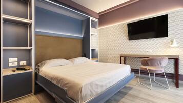 A modern hotel room with a bed, built-in shelving, a desk, and a TV.
