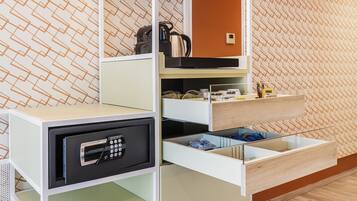 Une chambre d’hôtel moderne dotée d’un coffre-fort intégré, d’un minibar et d’un meuble de rangement avec une façade en verre.