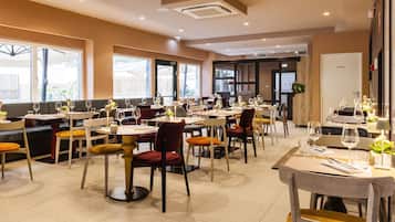 Un restaurante con varias mesas y sillas, ventanas amplias y una sala privada.